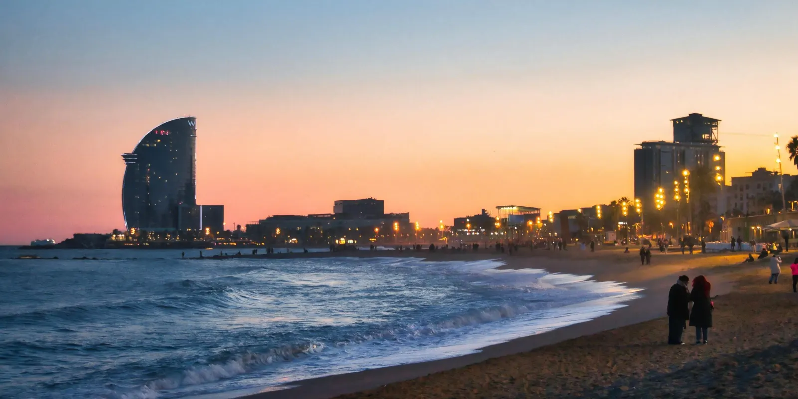 Pareja paseando por la playa de la Barceloneta al atardecer, con el hotel W al fondo